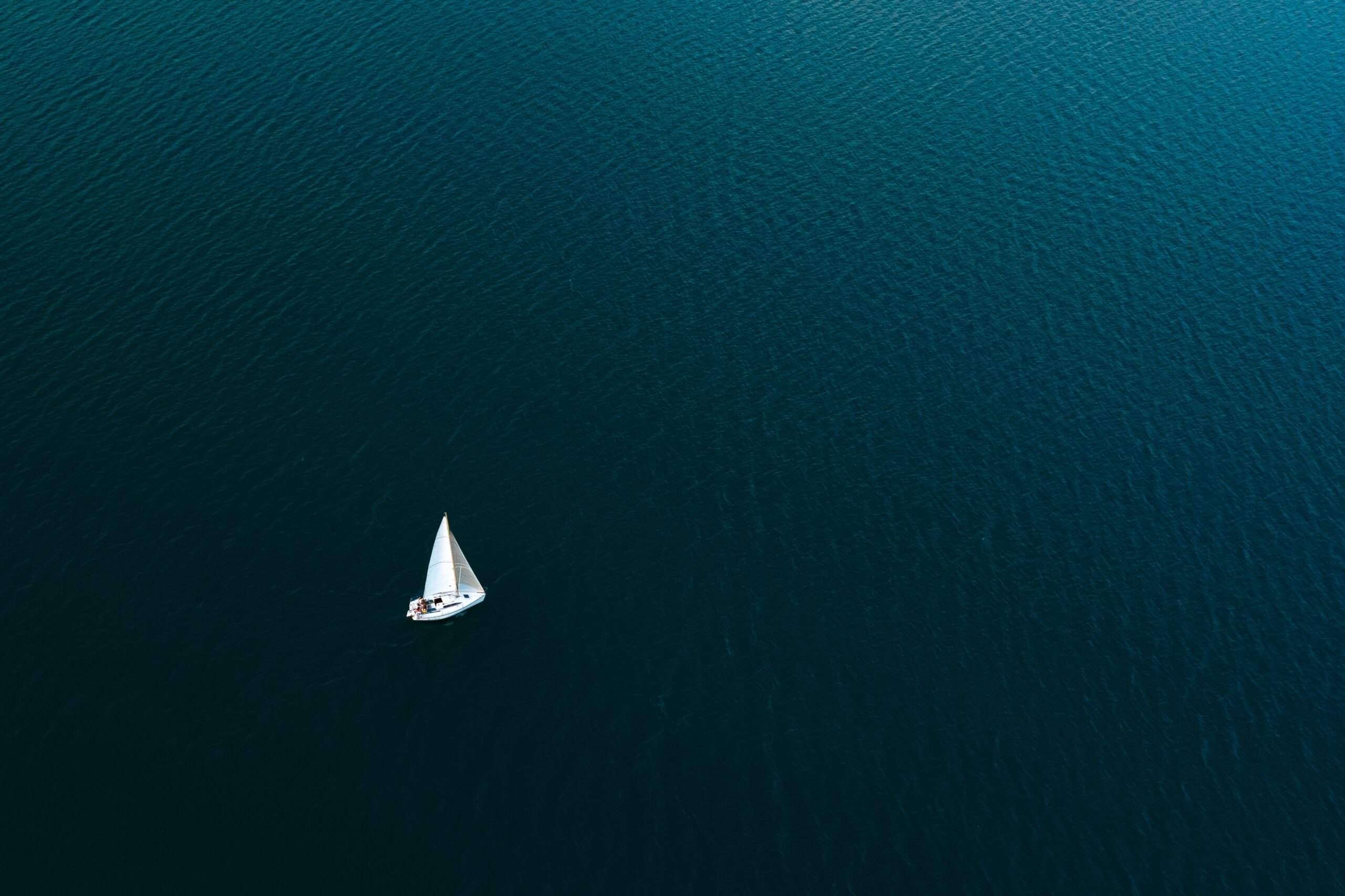 Lonely sailboat in the middle of a blue lake