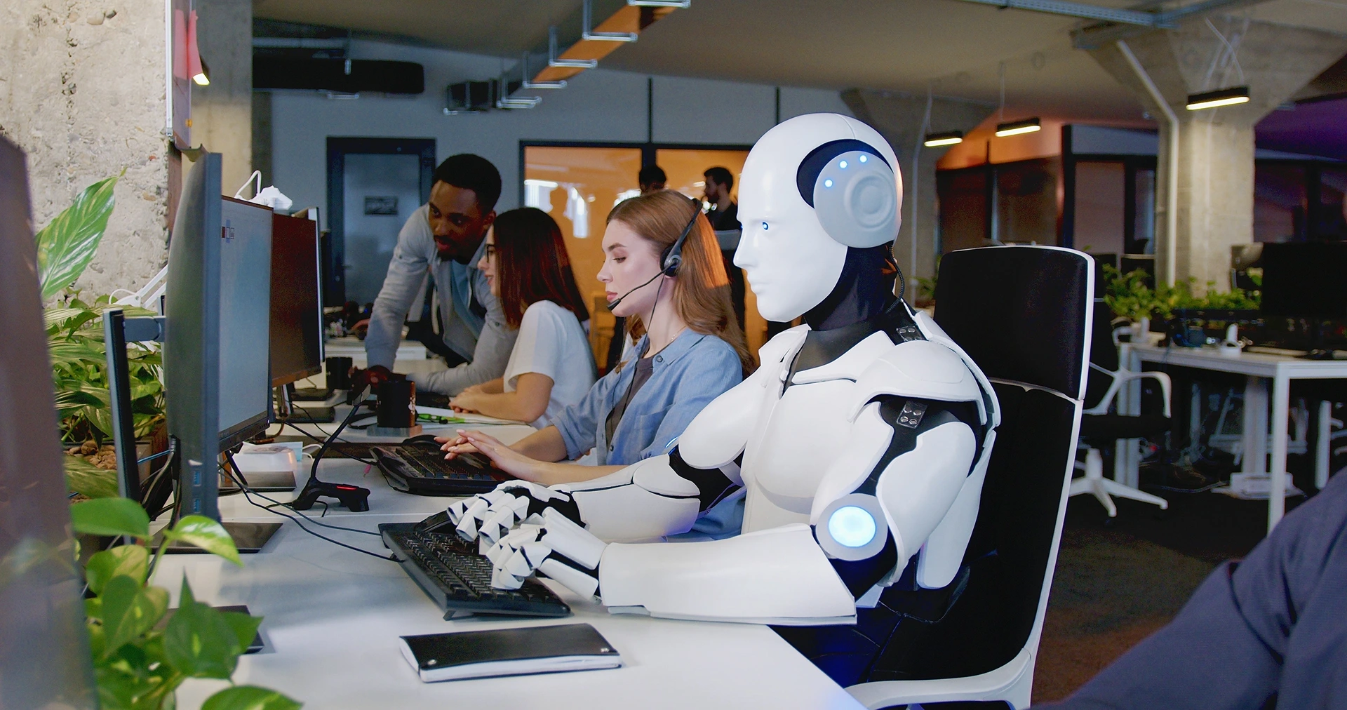 Robot working at computer among people